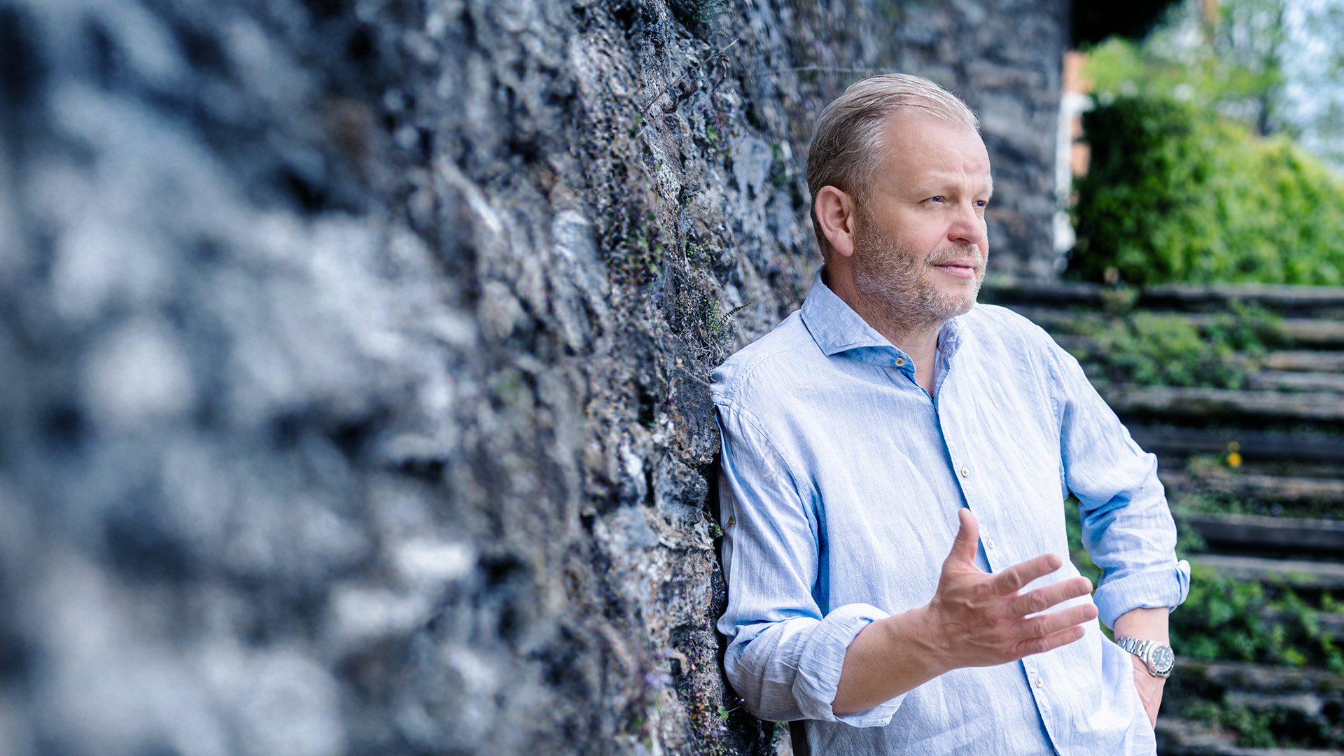 Unternehmertrainer Walter Baumgartner im Park lehnend an einer Mauer